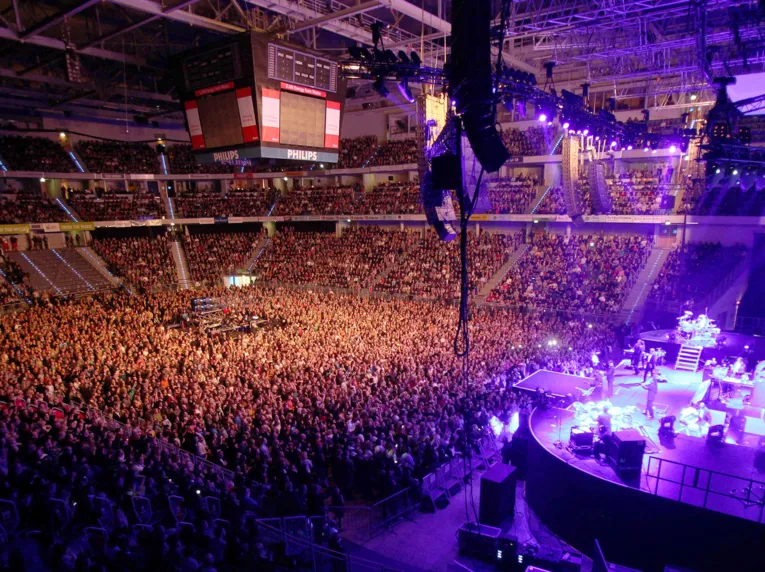 Färgglada strålkastare och tusentals människor: En inblick i TUI Arena under en konsert.