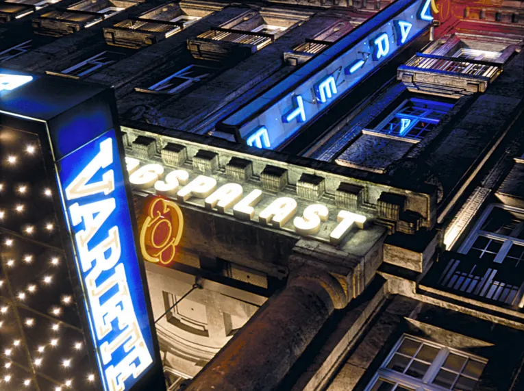 Beleuchtete Fassade des GOP Varieté-Theaters bei Nacht mit leuchtenden Schriftzügen und Neonlichtern an einem historischen Gebäude.