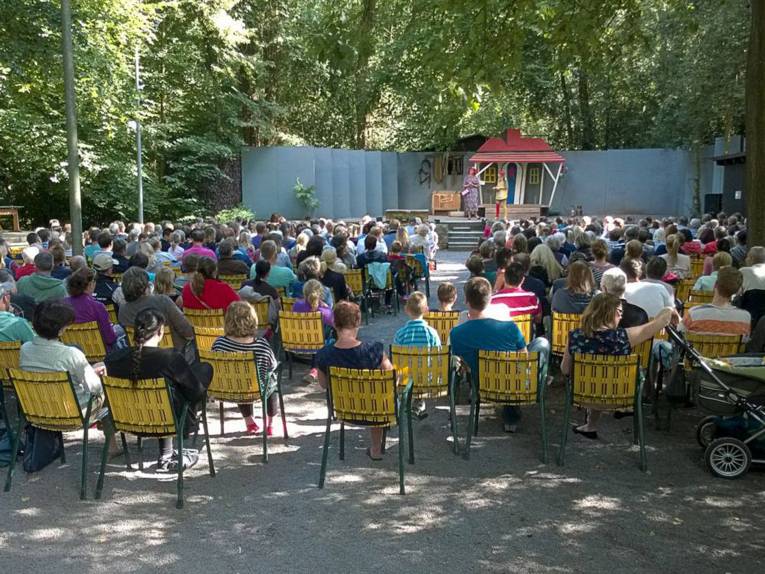 Bühne im Wald mit Zuschauern auf Campingstühlen davor