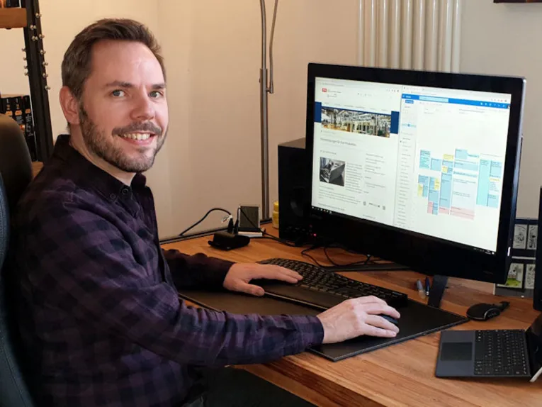 Mann an Schreibtisch mit Bildschirm und Tastatur