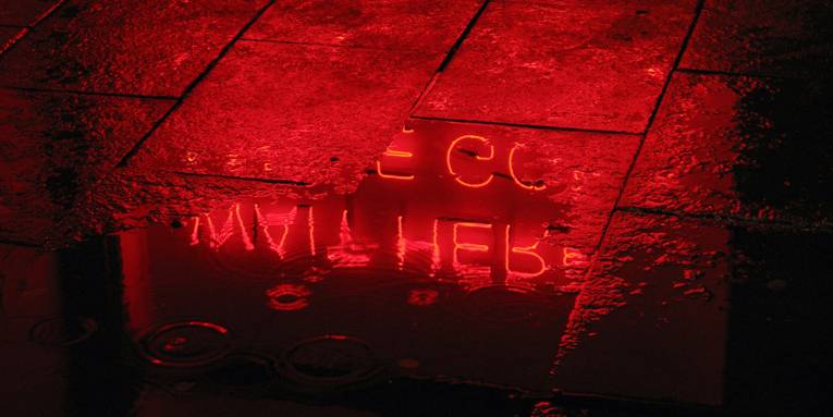Leuchtbuchstaben werden in einer Wasserpfütze reflektiert