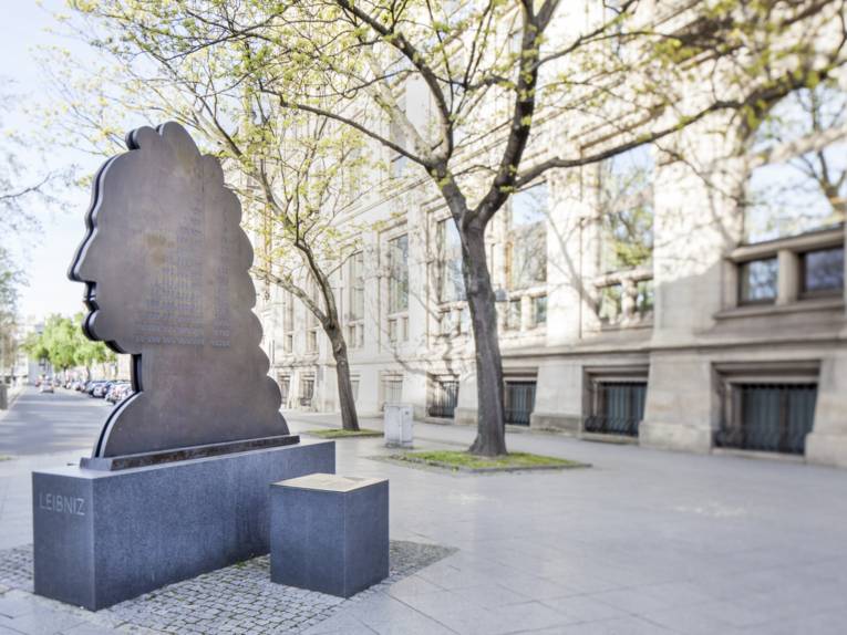 Denkmal im Form einer zwei Meter hohen, flachen Kopfsilhouette auf einem Bürgersteig vor einer Häuserfront.