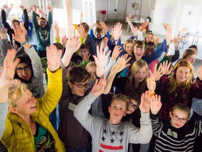 Kinder recken die Hände in die Höhe.