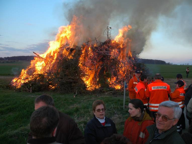 Brandmænd og mennesker foran en flammende påskebrand