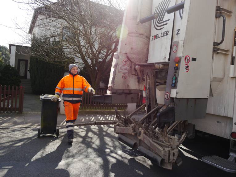 Mann mit Mülltonnen und Müllauto