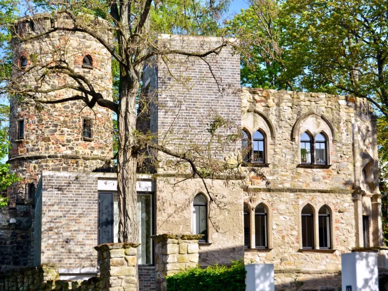 Burgähnliches Gebäude hinter Bäumen
