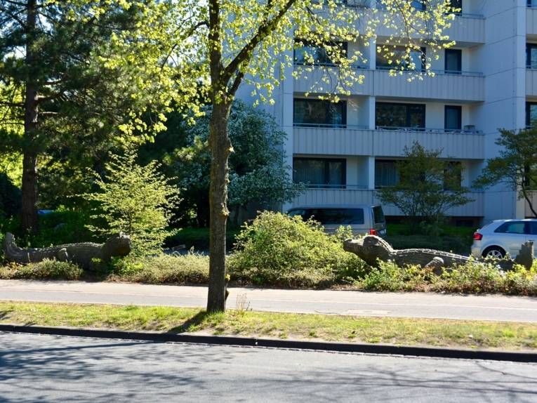 Steinerne Krokodile vor mehrgeschössigem Wohnhaus