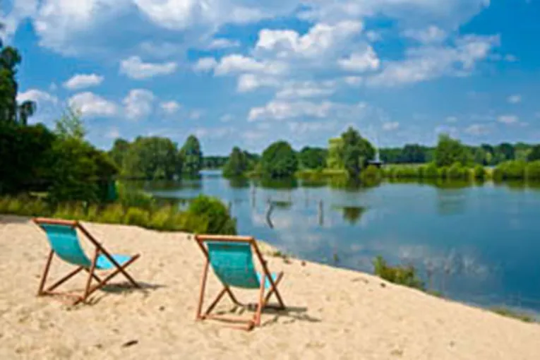 Two sun loungers aligned on the beach with a view of the water.