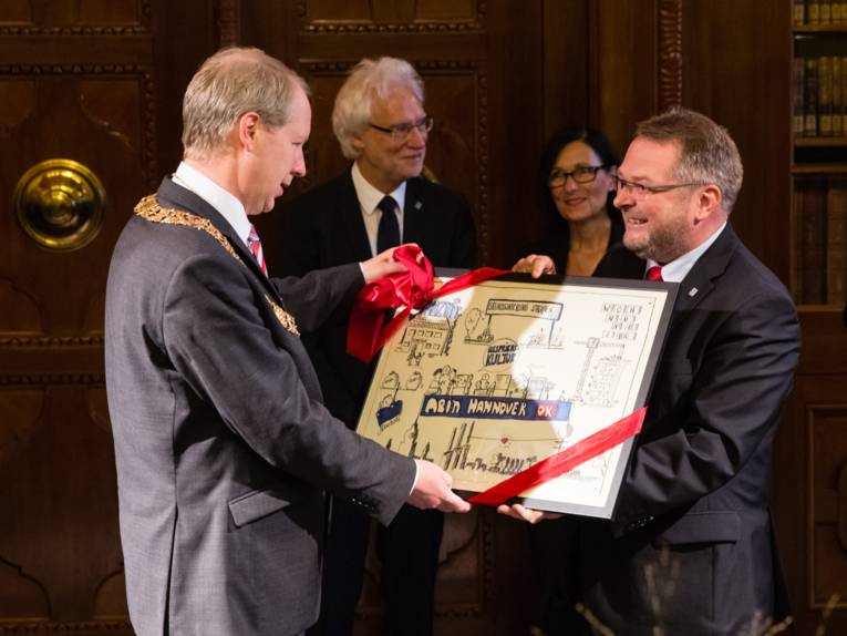 Stefan Schostok erhält von Thomas Hermann einen Bilderrahmen mit Karikaturen