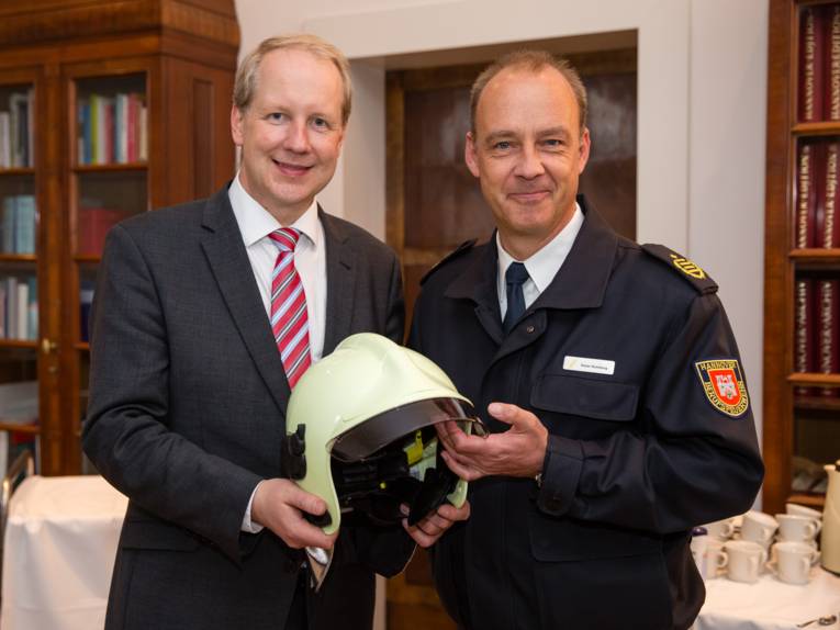 Stefan Schostok und Dieter Rohrberg präsentieren den Helm, den der neue OB geschenkt bekommt