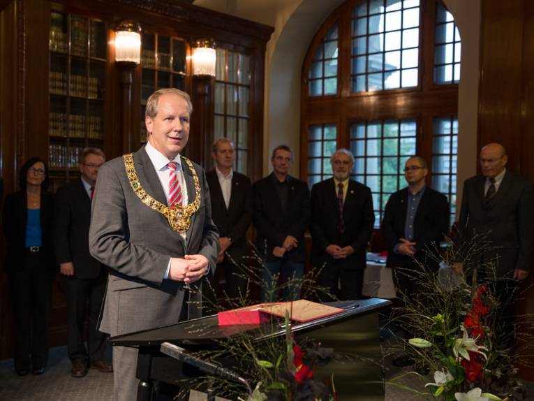 Stefan Schostok mit der Amtskette des Oberbürgermeisters am Rednerpult in der Ratsstube, im Hintergrund Vertreter der Ratsfraktionen