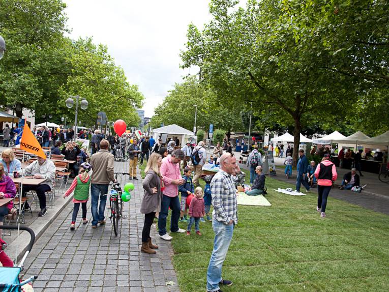Besucher flanieren über Rollrasen und sitzen zum Essen an Tischen