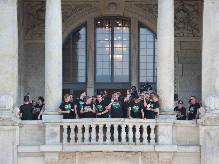 Menschen vor und in einem Rathaus. 