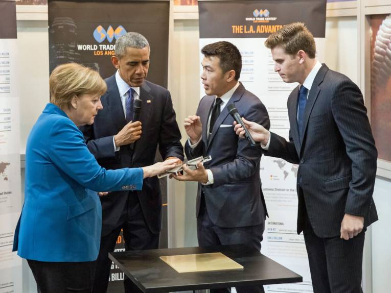 Ein Mann präsentiert anderen Menschen ein Objekt.