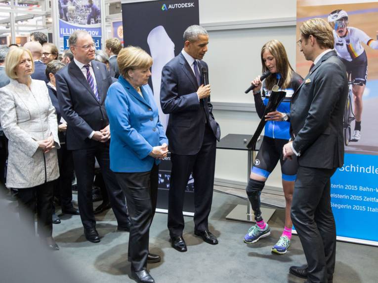 Frau mit Beinprothese zeigt anderen Leuten ein Bauteil.