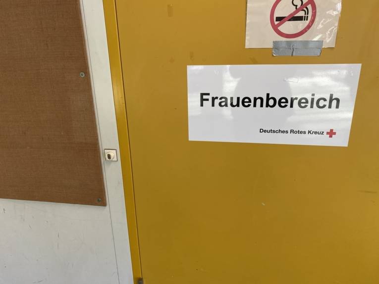 Schild an einer gelben Tür, auf der ein Schild mit der Aufschrift "Frauenbereich" steht. 