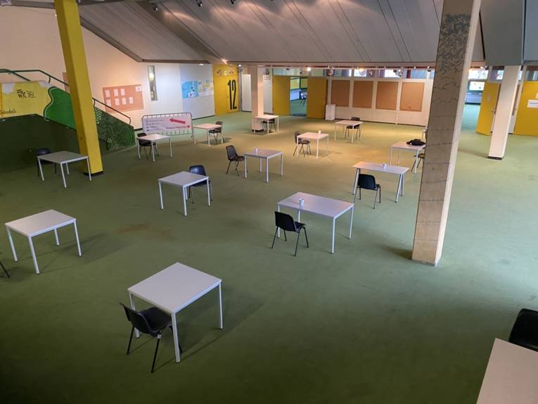 Eine Halle mit Tischen und Stühlen von oben. 