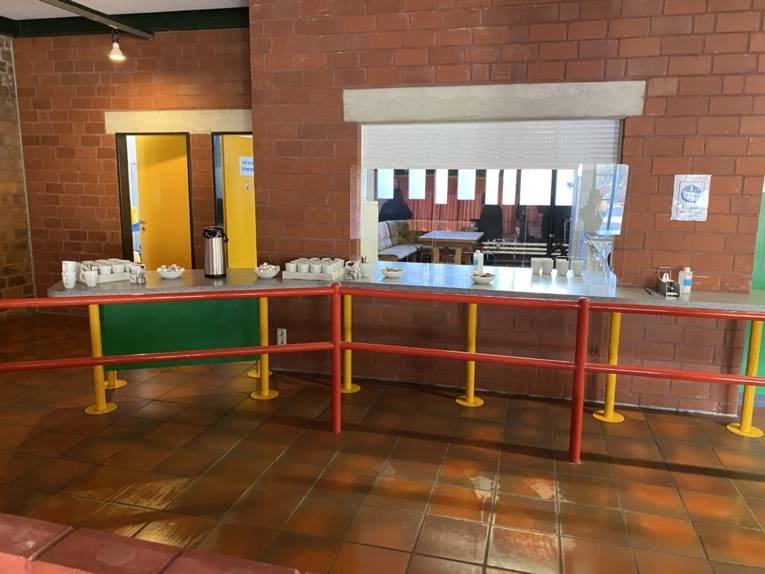 Nische zu einer Küche. Davor Tische mit Tassen. 