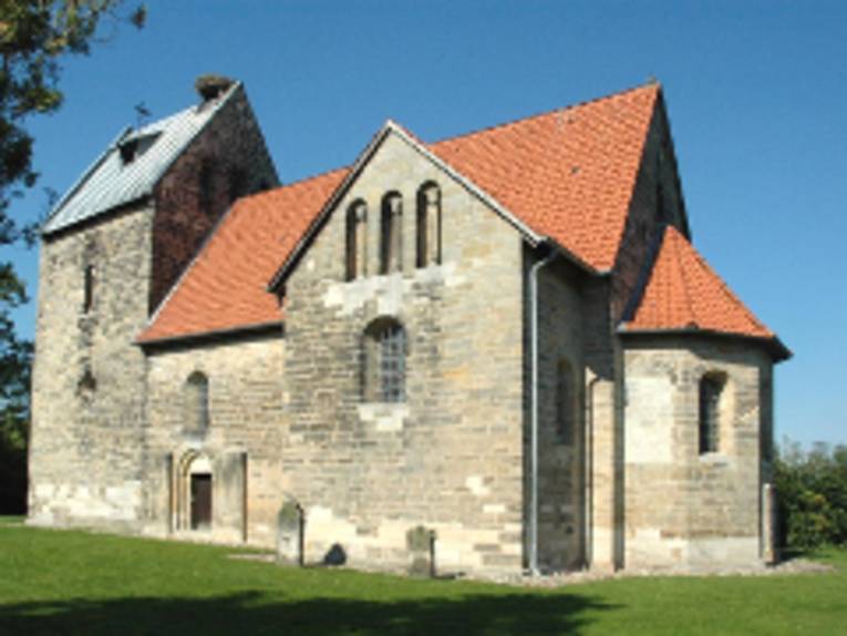 Blick von außen auf ein romanisches Kirchengebäude.
